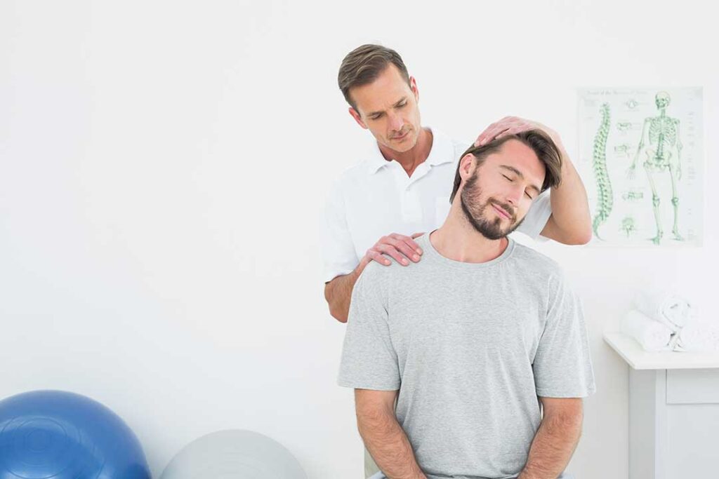 Adult reviewing a back pain diagram while standing beside a chair and walking shoes in a bright home setting.