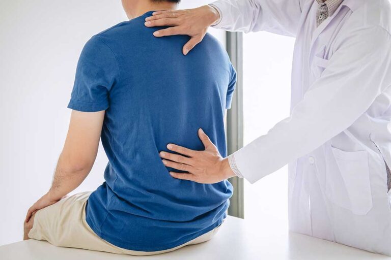 A clinician discusses mobility exercises with an adult seated in an examination room.